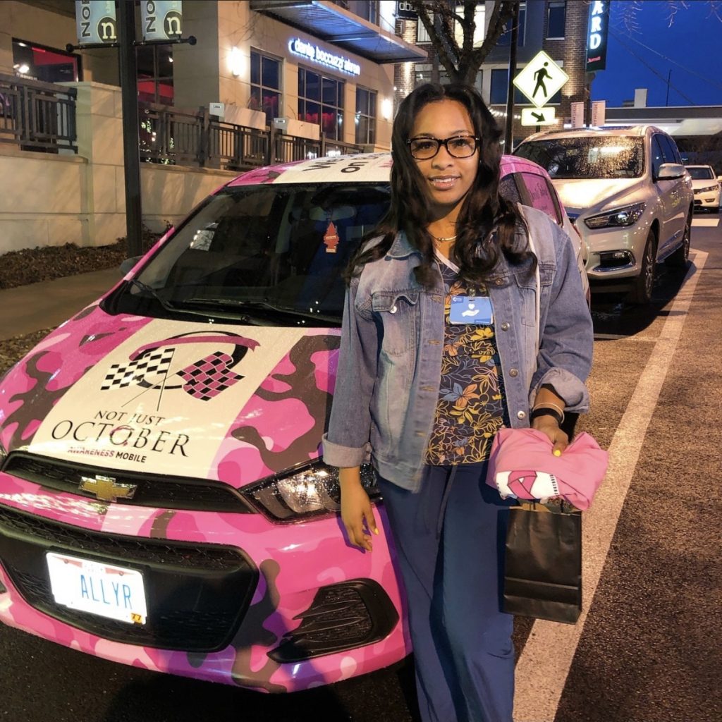 An individual served by Not Just October (NJO), pictured next to NJO's Cancer Awareness Mobile. An individual served by Not Just October (NJO), pictured next to NJO's Cancer Awareness Mobile.